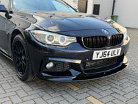 Load image into Gallery viewer, A close-up front three-quarter view of a glossy black BMW sedan parked on a paved driveway. The image highlights the front bumper, splitter, kidney grille, headlights, and black multi-spoke wheels.
