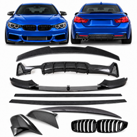 Load image into Gallery viewer, A set of black carbon-fiber-style rear bumper lip and diffuser accessories for a BMW, shown laid out on a white background with two blue BMW cars at the top used as reference vehicles. The set includes multiple rear bumper components, two kidney-grill-style inserts, and two long trim pieces.
