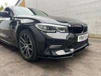 Load image into Gallery viewer, A black BMW sedan parked outdoors against a light gray wall, showing the front three-quarter view with the BMW kidney grille, headlights, and alloy wheels.
